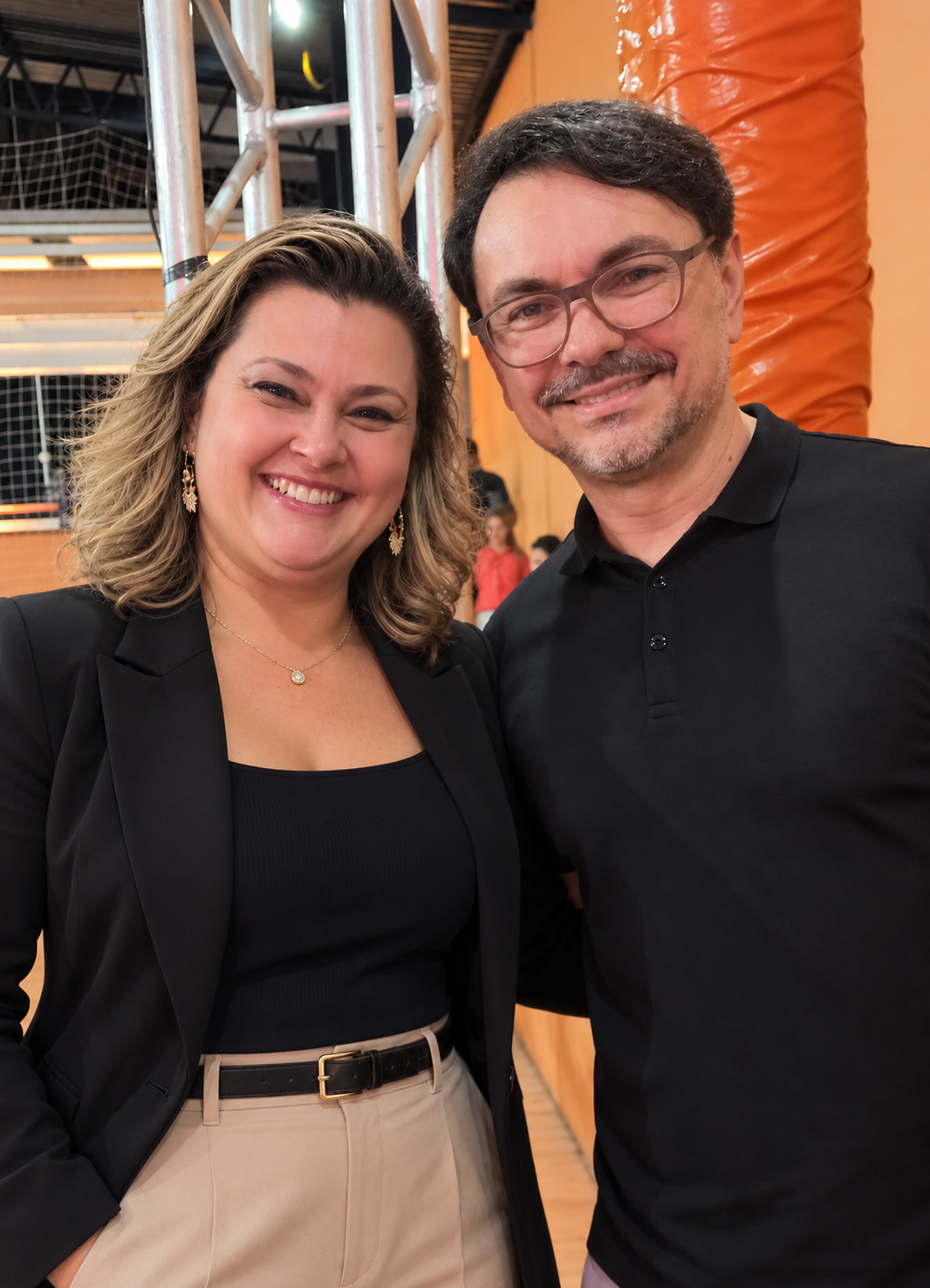 Claudiane sorrindo ao lado de um participante em evento